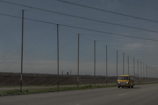 A car drives on a road covered with anti-drone nets to protect against drone attacks in Dnipropetrovsk region on April 17, 2026, amid the Russian invasion of Ukraine. (Photo by Roman PILIPEY / AFP)