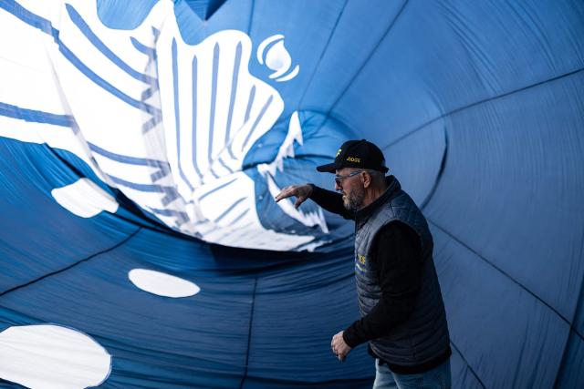 A participant walks through a kite depicting a whale while taking part in the 39th International Kite Festival (RICV) at the beach of Berck-sur-Mer, northern France, on April 18, 2026. Some 450 kite flyers from 28 countries attended the 39th Berck-sur-Mer International Kite Festival. The event is one of the largest of its kind and offers “a touch of magic” to counter the “gloom of everyday life”. (Photo by Sameer Al-DOUMY / AFP)