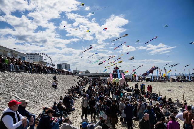 Attendees gather to watch kites flying in the sky during the 39th International Kite Festival (RICV) at the beach of Berck-sur-Mer, northern France, on April 18, 2026. Some 450 kite flyers from 28 countries attended the 39th Berck-sur-Mer International Kite Festival. The event is one of the largest of its kind and offers “a touch of magic” to counter the “gloom of everyday life”. (Photo by Sameer Al-DOUMY / AFP)