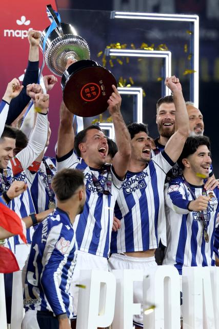 Real Sociedad's Spanish forward #10 Mikel Oyarzabal and teammates celebrate with the trophy at the end the Copa del Rey (King's Cup) final football match between Club Atletico de Madrid and Real Sociedad at La Cartuja stadium in Seville on April 18, 2026. Real Sociedad won Atletico Madrid 4-3 on penalties. (Photo by Thomas COEX / AFP)