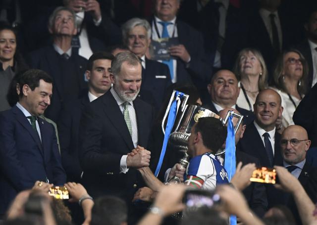 Spain's King Felipe VI (C) flanked by President of the Andalusia regional government Juanma Moreno (C,L) and Spain's Spanish coach Luis de la Fuente (R) handles the trophy to Real Sociedad's Spanish forward #10 Mikel Oyarzabal at the end the Copa del Rey (King's Cup) final football match between Club Atletico de Madrid and Real Sociedad at La Cartuja stadium in Seville on April 18, 2026. Real Sociedad won Atletico Madrid 4-3 on penalties. (Photo by CRISTINA QUICLER / AFP)