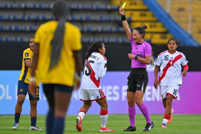 Brazilian referee Daiane Muniz shows a yellow card to Peru's midfielder #15 Luz Campoverde during the CONMEBOL Nations League Women football match between Ecuador and Peru at the Olimpico Atahualpa stadium in Quito, on April 18, 2026. (Photo by Rodrigo BUENDIA / AFP)