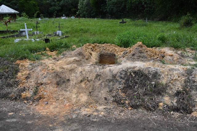 A view of an open grave at the cemetery of Cumuto, Trinidad and Tobago, taken on April 18, 2026. The remains of at least 50 infants and six adults were discovered on April 18, 2026, after they had apparently been discarded at a cemetery in Trinidad and Tobago, police said. (Photo by Curtis Chase / AFP)