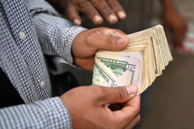 A cattle rancher counts cash after selling livestock at the municipal market known as the Tiangue in San Rafael Cedros, Cuscatlan department, El Salvador on April 18, 2026. Held mainly on Saturdays, the traditional market dates back to colonial times and serves as a key economic and social hub where hundreds of small-scale producers sell animals, agricultural goods, and food, often relying on these weekly sales as their primary source of income. (Photo by Marvin RECINOS / AFP)