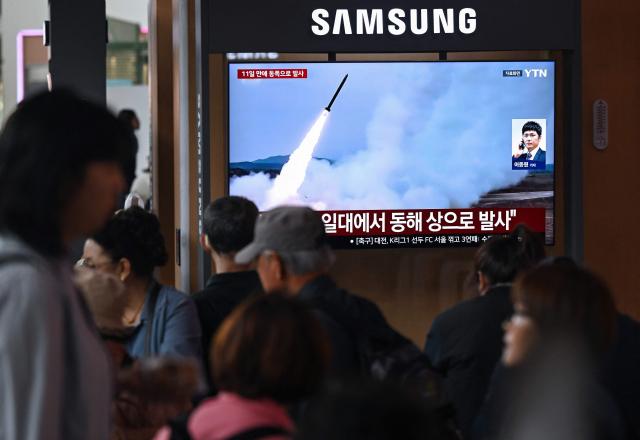 People watch a television screen showing a news broadcast with file footage of a North Korean missile test, at a train station in Seoul on April 19, 2026. North Korea test-fired multiple ballistic missiles on April 19, South Korea's military said, the latest in a recent flurry of launches by the nuclear-armed state. (Photo by Jung Yeon-je / AFP)