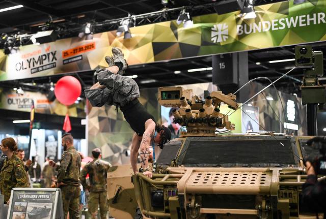 (FILES) A visitor performs on a reconnaissance vehicle of the German Federal army Bundeswehr at their booth at the FIBO trade show for health, fitness and wellness in Cologne, western Germany on April 16, 2026. Obstacle courses, combat demonstrations, daily raffles where visitors can win water bottles, mugs, T-shirts and backpacks in khaki and brown tones, as well as a small barbecue: the Bundeswehr is using every marketing trick in the book to attract new soldiers. (Photo by Ina FASSBENDER / AFP)
