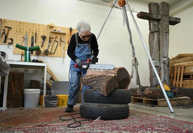 This picture taken on March 4, 2026, shows South Korean sculptor Kim Yun Shin using a chainsaw to create a work at her studio in Paju. In her 90s, South Korean sculptor Kim Yun Shin still wields a chainsaw with quiet focus, refining a craft she honed over decades spent far away from home. (Photo by Jung Yeon-je / AFP) / TO GO WITH AFP STORY  SKorea-Art BY Claire LEE