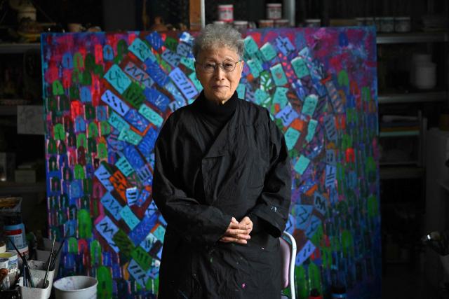 This picture taken on March 4, 2026, shows South Korean sculptor Kim Yun Shin dressed in overalls posing for a photo during an interview with AFP at her studio in Paju. In her 90s, South Korean sculptor Kim Yun Shin still wields a chainsaw with quiet focus, refining a craft she honed over decades spent far away from home. (Photo by Jung Yeon-je / AFP) / TO GO WITH AFP STORY  SKorea-Art BY Claire LEE