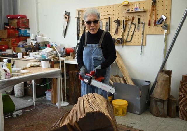 This picture taken on March 4, 2026, shows South Korean sculptor Kim Yun Shin using a chainsaw to create a work at her studio in Paju. In her 90s, South Korean sculptor Kim Yun Shin still wields a chainsaw with quiet focus, refining a craft she honed over decades spent far away from home. (Photo by Jung Yeon-je / AFP) / TO GO WITH AFP STORY  SKorea-Art BY Claire LEE