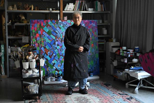 This picture taken on March 4, 2026, shows South Korean sculptor Kim Yun Shin dressed in overalls posing for a photo during an interview with AFP at her studio in Paju. In her 90s, South Korean sculptor Kim Yun Shin still wields a chainsaw with quiet focus, refining a craft she honed over decades spent far away from home. (Photo by Jung Yeon-je / AFP) / TO GO WITH AFP STORY  SKorea-Art BY Claire LEE