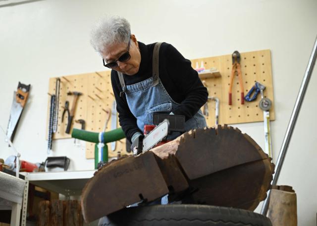 This picture taken on March 4, 2026, shows South Korean sculptor Kim Yun Shin using a chainsaw to create a work at her studio in Paju. In her 90s, South Korean sculptor Kim Yun Shin still wields a chainsaw with quiet focus, refining a craft she honed over decades spent far away from home. (Photo by Jung Yeon-je / AFP) / TO GO WITH AFP STORY  SKorea-Art BY Claire LEE