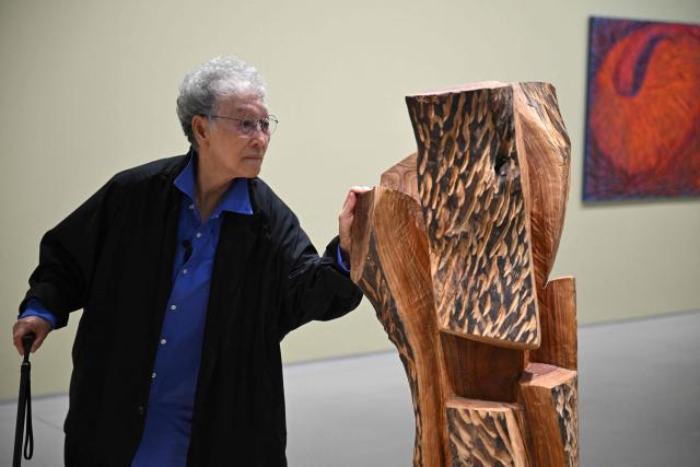 This picture taken on March 11, 2026, shows South Korean sculptor Kim Yun Shin looking at her works in her retrospective exhibition, titled "Two Be One", at Hoam Museum of Art in Yongin. In her 90s, South Korean sculptor Kim Yun Shin still wields a chainsaw with quiet focus, refining a craft she honed over decades spent far away from home. (Photo by Jung Yeon-je / AFP) / TO GO WITH AFP STORY  SKorea-Art BY Claire LEE