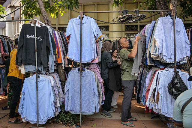 People shop for clothes at a stall along a street in Surabaya on April 19, 2026. (Photo by JUNI KRISWANTO / AFP)