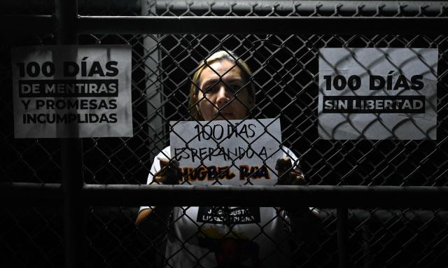 A relative of a Venezuelan political prisoner holds a sign during a vigil marking 100 days since they began calling for their release outside El Rodeo I prison in Guatire, Miranda state, Venezuela on April 18, 2026. Under pressure from Washington, Venezuela's interim president Delcy Rodriguez pushed through an amnesty law that provided for the release of hundreds of political prisoners. The amnesty came into force on February 19, 2026, but it is not automatic, as it requires the benefit to be applied for through the courts. (Photo by Maryorin Mendez / AFP)