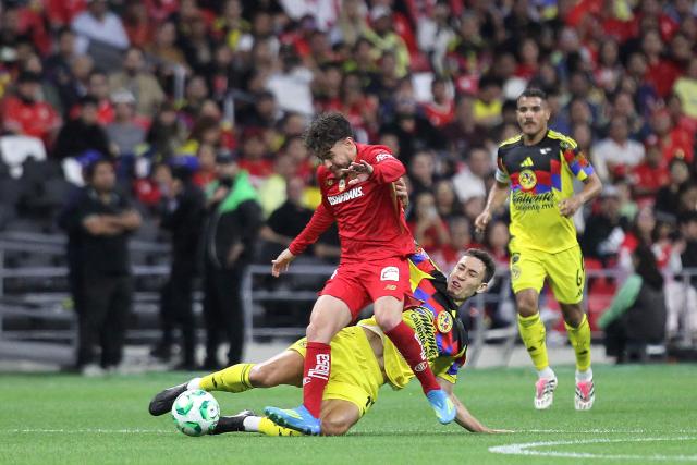 Toluca's midfielder #10 Jesus Angulo (L) and America's Brazilian midfielder #17 Rodrigo Dourado (R) fight for the ball during the Liga MX Clausura tournament football match between America and Toluca at the Azteca Stadium in Mexico City on April 18, 2026. (Photo by Victor CRUZ / AFP)