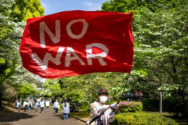 A demonstrator holds a flag reading "No War" during the "No war! Don’t change the Constitution!" rally outside the main gate of the National Diet Building, to call for the protection of Article 9 of the Constitution of Japan, in Tokyo on April 19, 2026. Article 9 is a clause stipulating that the Japanese people have renounced war as a sovereign right of the nation and the threat or use of force as means of settling international disputes (Photo by Philip FONG / AFP)