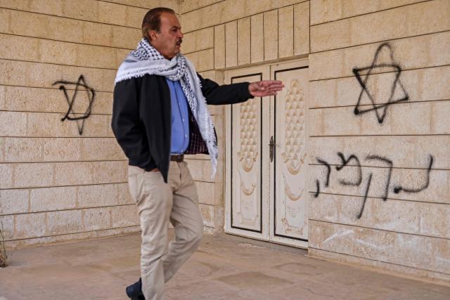 A Palestinian man gestures to a Hebrew graffiti on the wall of a house following a reported attack by Israeli settlers in Turmus Ayya village, north of Ramallah in the Israeli-occupied West Bank on April 19, 2026. Violence in the West Bank, which Israel has occupied since 1967, has risen sharply since the October 7, 2023 Hamas attack on Israel triggered the Gaza war. There has also been a spike in deadly attacks by Israeli settlers in the West Bank since the start of the Iran war on February 28, Palestinian authorities and the United Nations have said. (Photo by Zain JAAFAR / AFP)