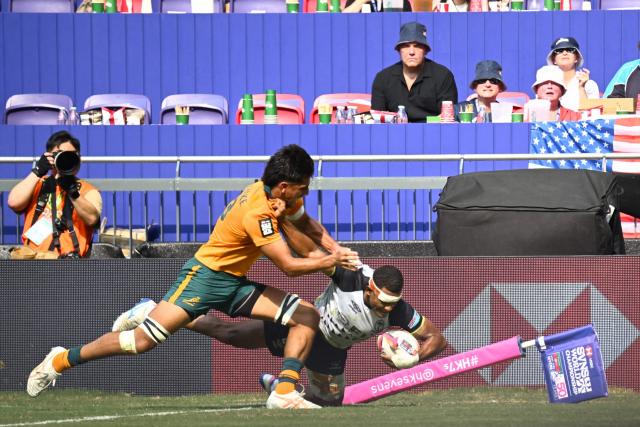 Fiji's Douglas Daveta (R) scores a try against Australia's Aden Ekanayake (L) during their 5th Place Play-Off match on the third day of the 2026 Rugby Sevens Hong Kong tournament at Kai Tak Stadium in Hong Kong on April 19, 2026. (Photo by Peter PARKS / AFP)