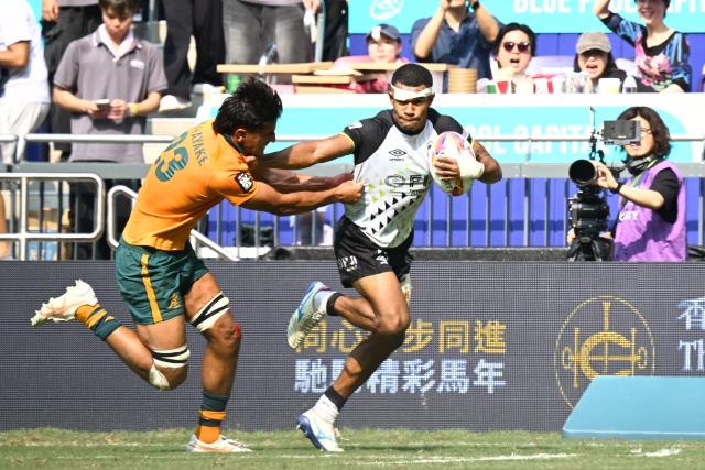 Fiji's Douglas Daveta (R) scores a try against Australia's Aden Ekanayake (L) during their 5th Place Play-Off match on the third day of the 2026 Rugby Sevens Hong Kong tournament at Kai Tak Stadium in Hong Kong on April 19, 2026. (Photo by Peter PARKS / AFP)