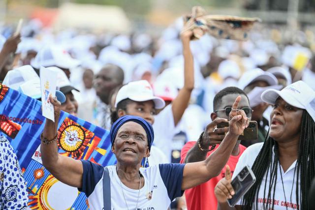 A faithful cheers as Pope Leo XIV (unssen) arrives in the Popemobile to lead a Holy Mass in Kalimba on the seventh day of an 11-day apostolic journey to Africa, on April 19, 2026. (Photo by Alberto PIZZOLI / AFP)