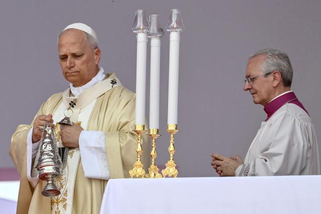 CORRECTION / Pope Leo XIV (L) swings the thurible as he leads a Holy Mass in Kilamba on the seventh day of an 11-day apostolic journey to Africa, on April 19, 2026. (Photo by Alberto PIZZOLI / AFP) / “The erroneous mention[s] appearing in the metadata of this photo by Alberto PIZZOLI has been modified in AFP systems in the following manner: [ Kilamba] instead of [Kalimba]. Please immediately remove the erroneous mention[s] from all your online services and delete it (them) from your servers. If you have been authorized by AFP to distribute it (them) to third parties, please ensure that the same actions are carried out by them. Failure to promptly comply with these instructions will entail liability on your part for any continued or post notification usage. Therefore we thank you very much for all your attention and prompt action. We are sorry for the inconvenience this notification may cause and remain at your disposal for any further information you may require.”