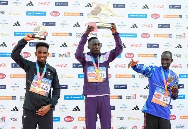 (L-R) Second placed Oqbe Kibrom from Eritrea, winner Kenya's Fanny Kiprotich and third placed Kenya's Charles Mneria celebrate with their trophies on the podium after the Vienna City Marathon (VCM) in Vienna, Austria, on April 19, 2026. (Photo by MAX SLOVENCIK / APA / AFP) / Austria OUT