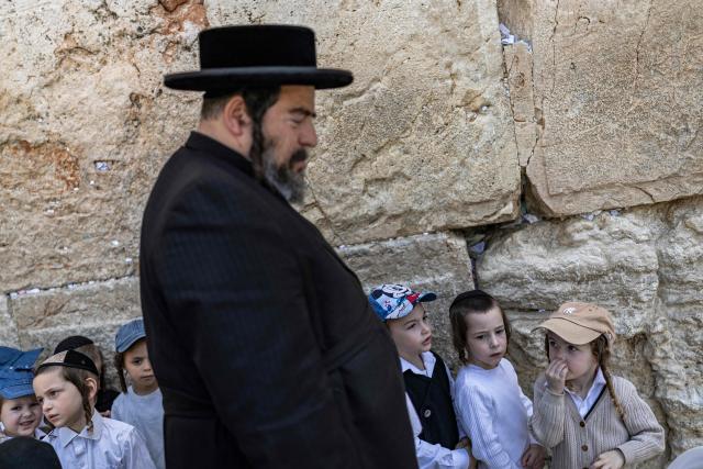 An Ultra-Orthodox man along with children visit the Western Wall in the old city of Jerusalem on April 19, 2026. (Photo by ilia YEFIMOVICH / AFP)