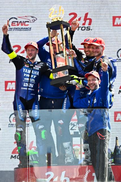 Yart Yamaha Official team's German formula EWC rider Marvin Fritz (L), Yart Yamaha Official team's Argentine formula EWC rider Leandro Mercado (2ndR) and Yart Yamaha Official team's Czech formula EWC rider Karel Hanika (R) hold the trophy in the podium after winning the 49th Le Mans 24-hours endurance moto race, in Le Mans, northwestern France, on April 19, 2026. (Photo by JULIEN DE ROSA / AFP)