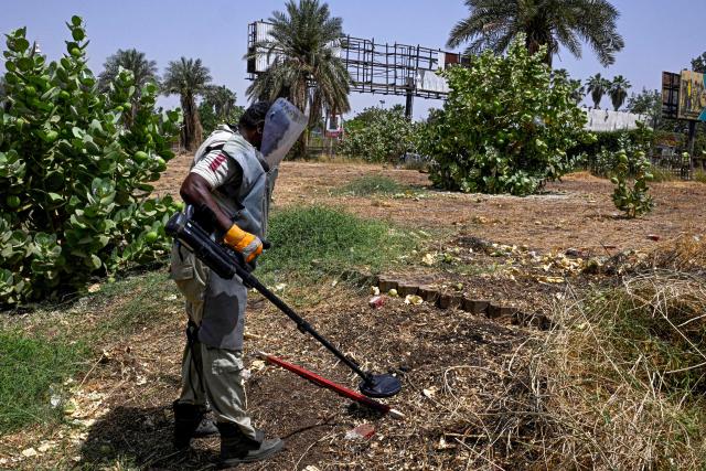 A member of Dutch Migration Council (DRC), and Jasmar Human Security Organization sweeps a metal detector as he searches for land mines in Al-Mugran Park in Khartoum on April 19, 2026. Khartoum's city centre, once home to bustling markets, towering businesses and wealthy districts, remains a ghost town, a mass grave and a minefield. Of the nearly four million people -- around half Khartoum's pre-war population -- who fled during the conflict, more than 1.8 million have returned over the past year. Yet fewer than 80,000 people have come back to central Khartoum, according to the United Nations. (Photo by Khaled DESOUKI / AFP)