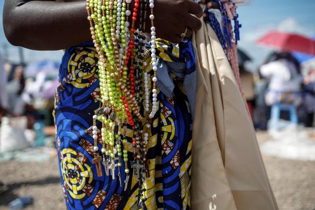 A vendor sells rosary beads ahead of the Holy Rosary Prayer lead by Pope Leo XIV on the esplanade in front of the "Mama Maxima" Shrine in Muxima on the seventh day of an 11-day apostolic journey to Africa, on April 19, 2026. (Photo by PHILL MAGAKOE / AFP)
