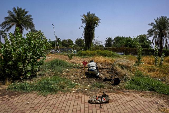 A member of the Dutch Migration Council (DRC), and Jasmar Human Security Organization uses a metal probe as he searches for land mines in Al-Mugran Park in Khartoum on April 19, 2026. Khartoum's city centre, once home to bustling markets, towering businesses and wealthy districts, remains a ghost town, a mass grave and a minefield. Of the nearly four million people -- around half Khartoum's pre-war population -- who fled during the conflict, more than 1.8 million have returned over the past year. Yet fewer than 80,000 people have come back to central Khartoum, according to the United Nations. (Photo by Khaled DESOUKI / AFP)