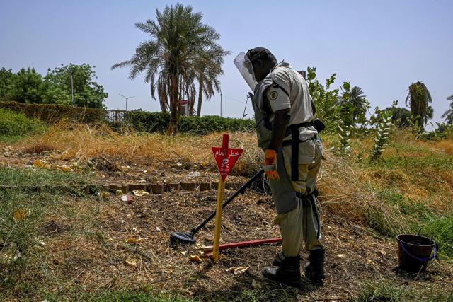 TOPSHOT - A member of the Dutch Migration Council (DRC), and Jasmar Human Security Organization sweeps a metal detector as he searches for land mines in Al-Mugran Park in Khartoum on April 19, 2026. Khartoum's city centre, once home to bustling markets, towering businesses and wealthy districts, remains a ghost town, a mass grave and a minefield. Of the nearly four million people -- around half Khartoum's pre-war population -- who fled during the conflict, more than 1.8 million have returned over the past year. Yet fewer than 80,000 people have come back to central Khartoum, according to the United Nations. (Photo by Khaled DESOUKI / AFP)