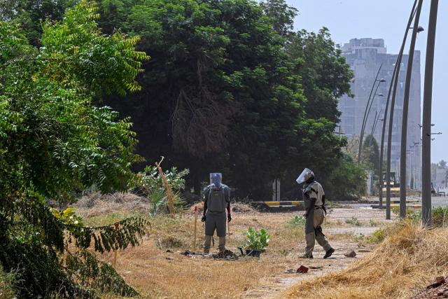 Members of the Dutch Migration Council (DRC), and Jasmar Human Security Organization search for land mines in Al-Mugran Park in Khartoum on April 19, 2026. Khartoum's city centre, once home to bustling markets, towering businesses and wealthy districts, remains a ghost town, a mass grave and a minefield. Of the nearly four million people -- around half Khartoum's pre-war population -- who fled during the conflict, more than 1.8 million have returned over the past year. Yet fewer than 80,000 people have come back to central Khartoum, according to the United Nations. (Photo by Khaled DESOUKI / AFP)