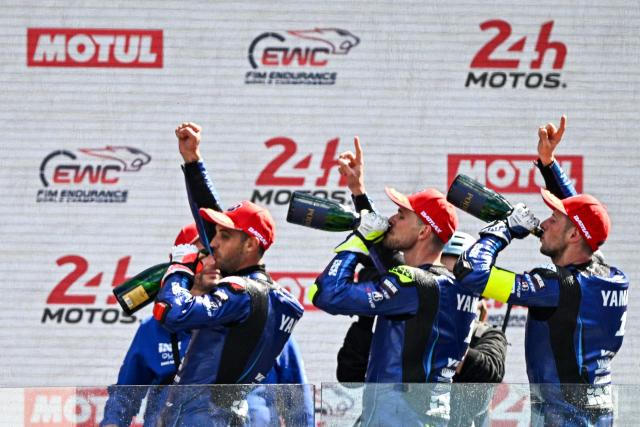 TOPSHOT - (FromL) Yart Yamaha Official team's Argentine formula EWC rider Leandro Mercado, Yart Yamaha Official team's Czech formula EWC rider Karel Hanika and Yart Yamaha Official team's German formula EWC rider Marvin Fritz celebrate on the podium after winning the 49th Le Mans 24-hours endurance moto race, in Le Mans, northwestern France, on April 19, 2026. (Photo by JULIEN DE ROSA / AFP)