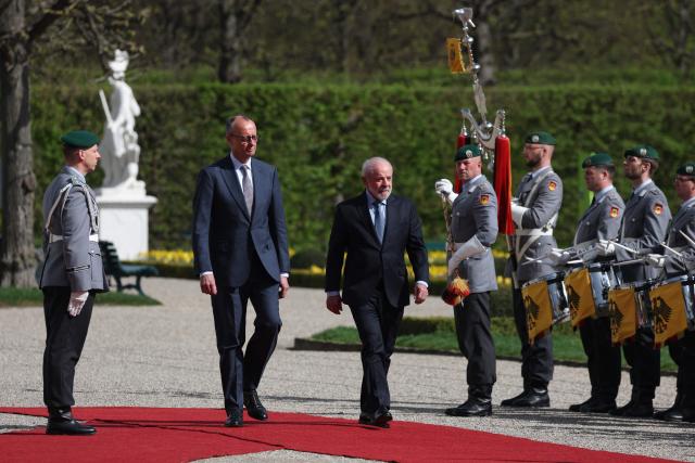 Brazil's President Luiz Inacio Lula Da Silva (R) and Germany's Chancellor Friedrich Merz review a military guard of honor during a welcoming ceremony at the Herrenhausen Palace in Hannover, Germany on April 19, 2026, ahead of their visit to the Hannover industrial trade fair. The fair opens its doors to the public on April 20 and will be running until April 24, 2026. (Photo by Odd ANDERSEN / AFP)