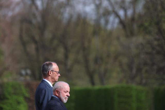 Brazil's President Luiz Inacio Lula Da Silva (R) and Germany's Chancellor Friedrich Merz stand as they review a military guard of honor during a welcoming ceremony at the Herrenhausen Palace in Hannover, Germany on April 19, 2026, ahead of their visit to the Hannover industrial trade fair. The fair opens its doors to the public on April 20 and will be running until April 24, 2026. (Photo by Odd ANDERSEN / AFP)