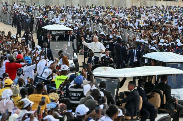 Pope Leo XIV (C) waves to the crowd as he arrives to lead a Holy Rosary Prayer on the esplanade in front of the "Mama Muxima" Shrine in Muxima on the seventh day of an 11-day apostolic journey to Africa, on April 19, 2026. (Photo by Alberto PIZZOLI / AFP)