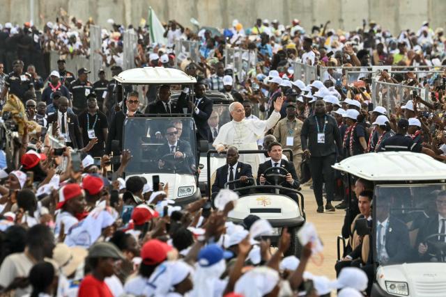 Pope Leo XIV (C) waves to the crowd as he arrives to lead a Holy Rosary Prayer on the esplanade in front of the "Mama Muxima" Shrine in Muxima on the seventh day of an 11-day apostolic journey to Africa, on April 19, 2026. (Photo by Alberto PIZZOLI / AFP)
