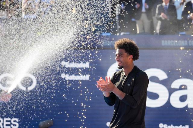 France's Arthur Fils celebratea on the podium after winning the men’s singles final against Russia's Andrey Rublev at the ATP Barcelona Open "Conde de Godo" tennis tournament in Barcelona, on April 19, 2026. Fils won 6-2, 7-6 (7/2) (Photo by Manaure Quintero / AFP)