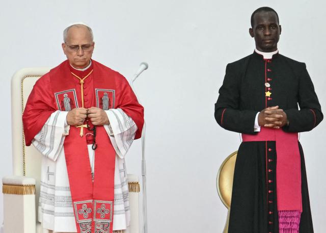 Pope Leo XIV (L) holds a rosary as he attends a Holy Rosary Prayer on the esplanade in front of the "Mama Muxima" Shrine in Muxima on the seventh day of an 11-day apostolic journey to Africa, on April 19, 2026. (Photo by Alberto PIZZOLI / AFP)