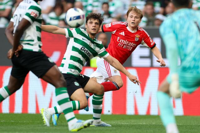 SL Benfica's Norwegian forward #21 Andreas Schjelderup  (R) wathces the ball challenged by Sporting Lisbon's Portuguese defender #72 Eduardo Quaresma during the Portuguese League football match between Sporting CP and SL Benfica at Jose Alvalade stadium in Lisbon, on April 19, 2026. (Photo by PATRICIA DE MELO MOREIRA / AFP)