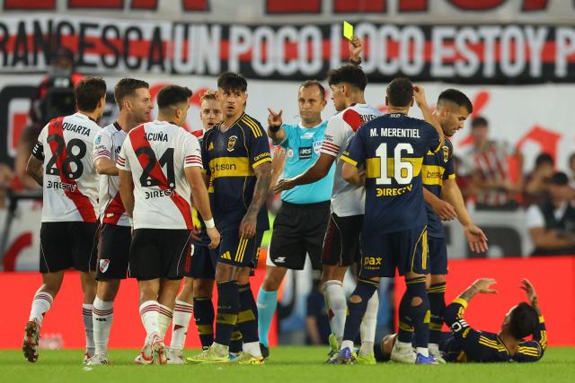 Argentine referee Dario Herrera shows a yellow card to River Plate's defender #21 Marcos Acuna during the Argentine Professional Football League 2026 Apertura Tournament match between River Plate and Boca Juniors at MAS Monumental stadium in Buenos Aires on April 19, 2026. (Photo by Alejandro PAGNI / AFP)