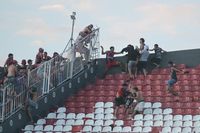 Fans of Cerro Porteno and Olimpia clash during the Paraguayan tournament football match between Olimpia and Cerro Porteno at the Defensores del Chaco Stadium in Asuncion on April 19, 2026. Several people were injured and at least a hundred were arrested following incidents that occurred during the Paraguayan football derby between Olimpia and Cerro Porteno, which was suspended in the first half in Asuncion on April 19, 2026. (Photo by Daniel DUARTE / AFP)