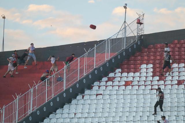 Fans of Cerro Porteno and Olimpia clash during the Paraguayan tournament football match between Olimpia and Cerro Porteno at the Defensores del Chaco Stadium in Asuncion on April 19, 2026. Several people were injured and at least a hundred were arrested following incidents that occurred during the Paraguayan football derby between Olimpia and Cerro Porteno, which was suspended in the first half in Asuncion on April 19, 2026. (Photo by Daniel DUARTE / AFP)