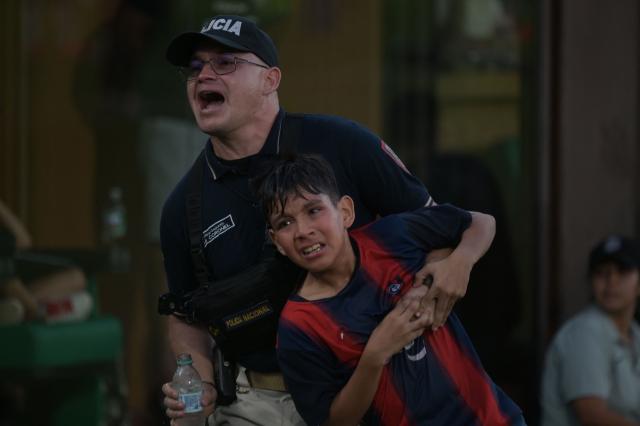 A police officer carries a Cerro Porteno fan after clashes between supporters and police during the Paraguayan tournament football match between Olimpia and Cerro Porteno at the Defensores del Chaco Stadium in Asunción on April 19, 2026. Several people were injured and at least a hundred were arrested following incidents that occurred during the Paraguayan football derby between Olimpia and Cerro Porteno, which was suspended in the first half in Asuncion on April 19, 2026. (Photo by Daniel DUARTE / AFP)
