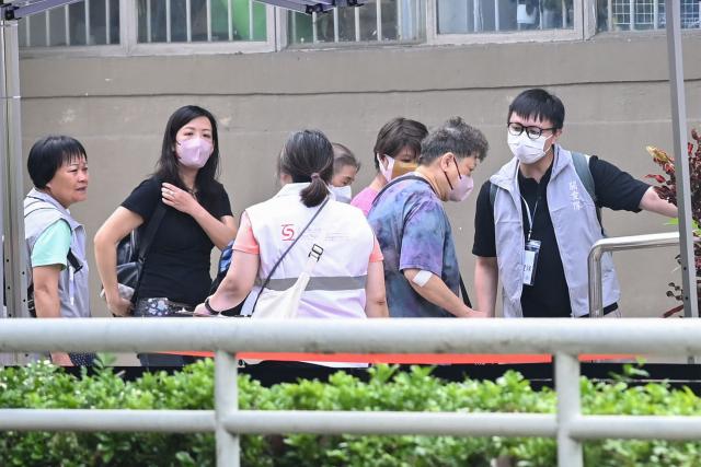 Residents of Wang Fuk Court residential estate arrive to return to their apartments in Hong Kong on April 20, 2026. Thousands of Hong Kong residents who lost their homes in a massive fire last year are set to return from April 20 for the first time to collect what is left of their belongings. (Photo by Peter PARKS / AFP)