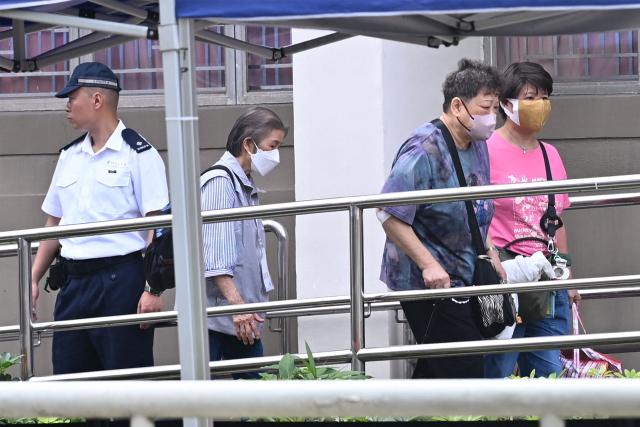 Residents of Wang Fuk Court residential estate arrive to return to their apartments in Hong Kong on April 20, 2026. Thousands of Hong Kong residents who lost their homes in a massive fire last year are set to return from April 20 for the first time to collect what is left of their belongings. (Photo by Peter PARKS / AFP)