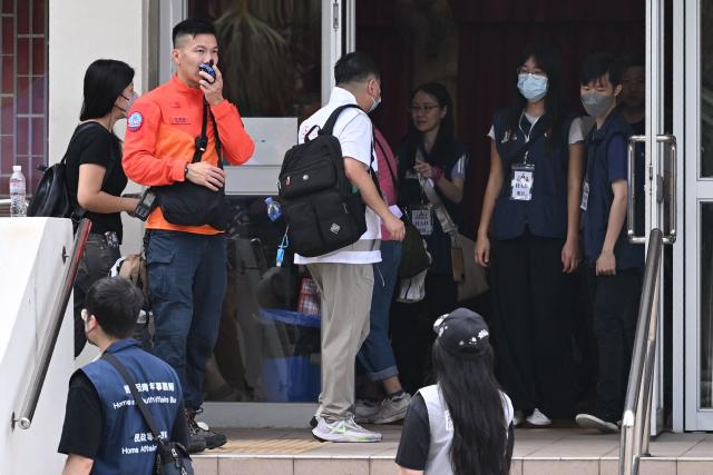 Residents of Wang Fuk Court residential estate arrive to return to their apartments in Hong Kong on April 20, 2026. Thousands of Hong Kong residents who lost their homes in a massive fire last year are set to return from April 20 for the first time to collect what is left of their belongings. (Photo by Peter PARKS / AFP)