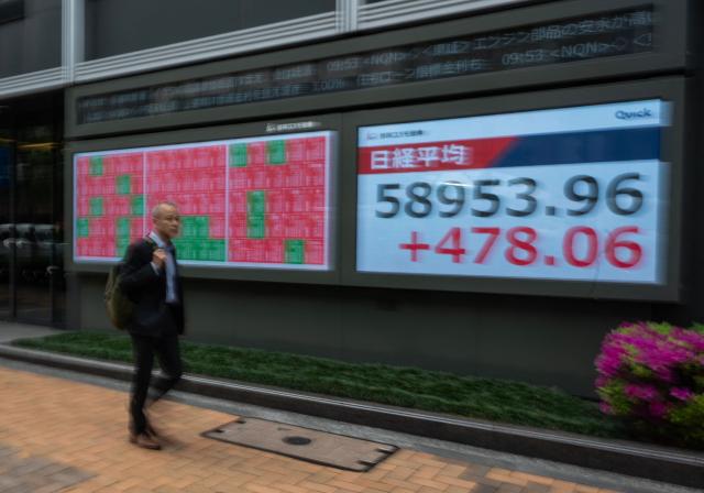 A man walks past a display of the Nikkei Stock Average near the Tokyo Stock Exchange in Tokyo on April 20, 2026. (Photo by Andrew CABALLERO-REYNOLDS / AFP)