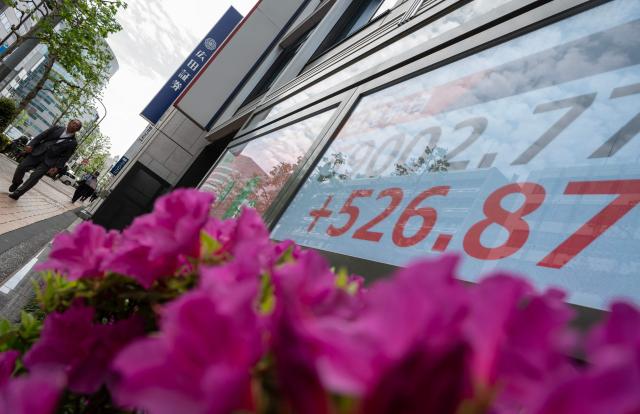 A man walks past a display of the Nikkei Stock Average near the Tokyo Stock Exchange in Tokyo on April 20, 2026. (Photo by Andrew CABALLERO-REYNOLDS / AFP)